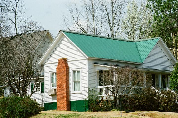 Brick chimney on a white clapboard house with a green metal roof